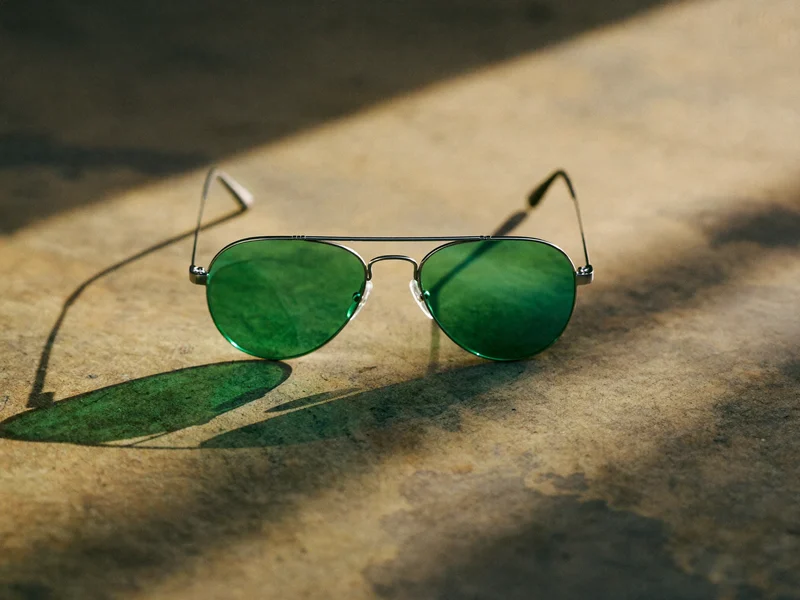 Ochelari de soare aviator cu lentile verzi pe beton încălzit de soare